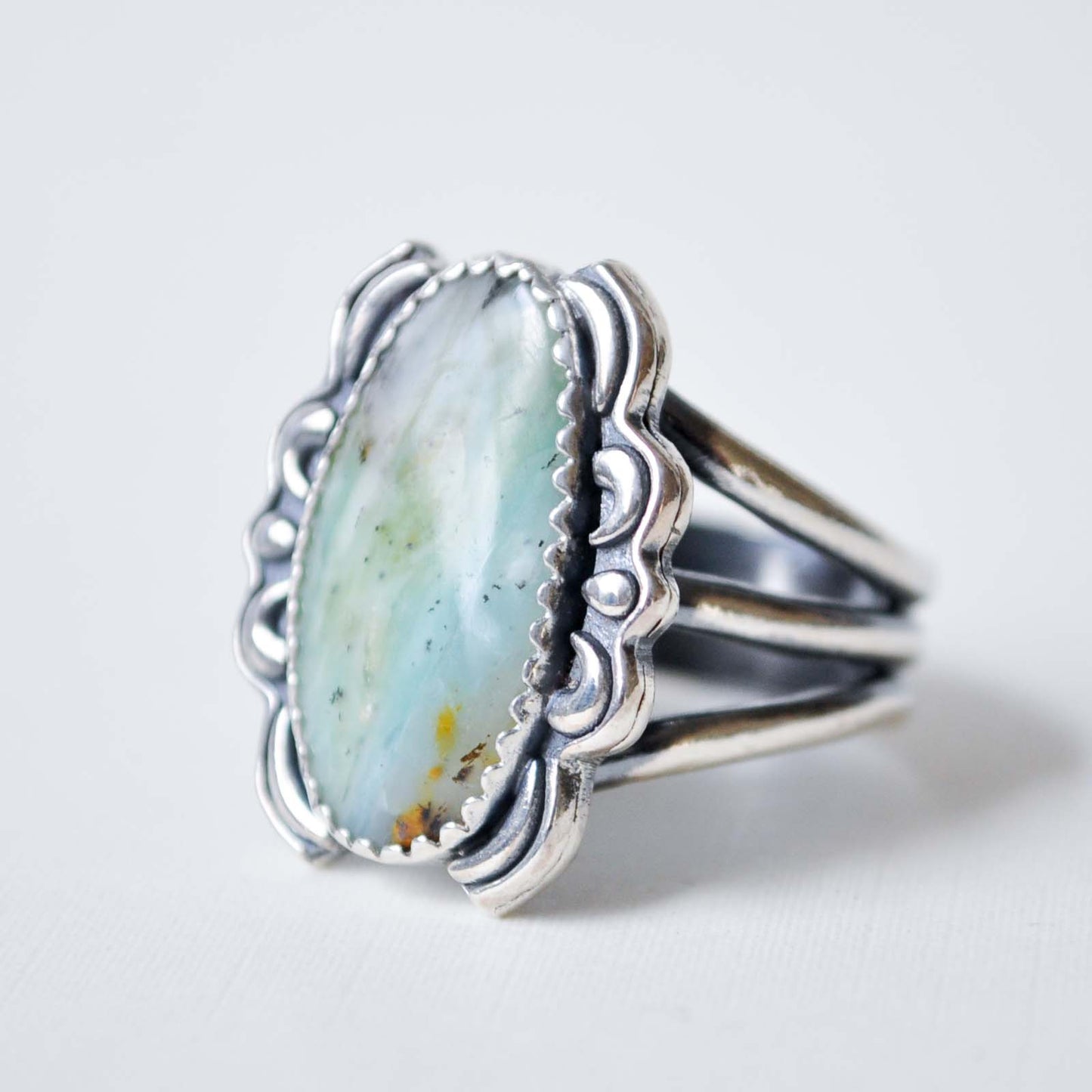 Silver ring with a large turquoise stone on a light gray background
