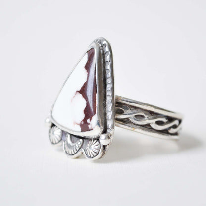 Silver ring with a white stone on a light gray background