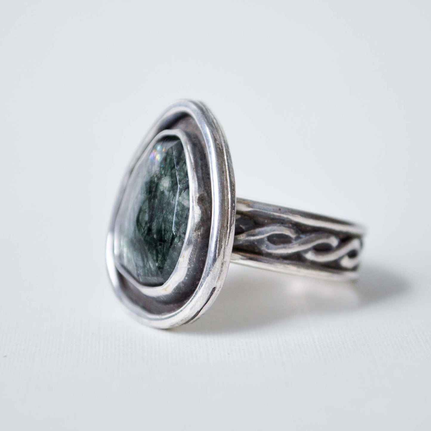 Silver ring with a green stone on a light gray background