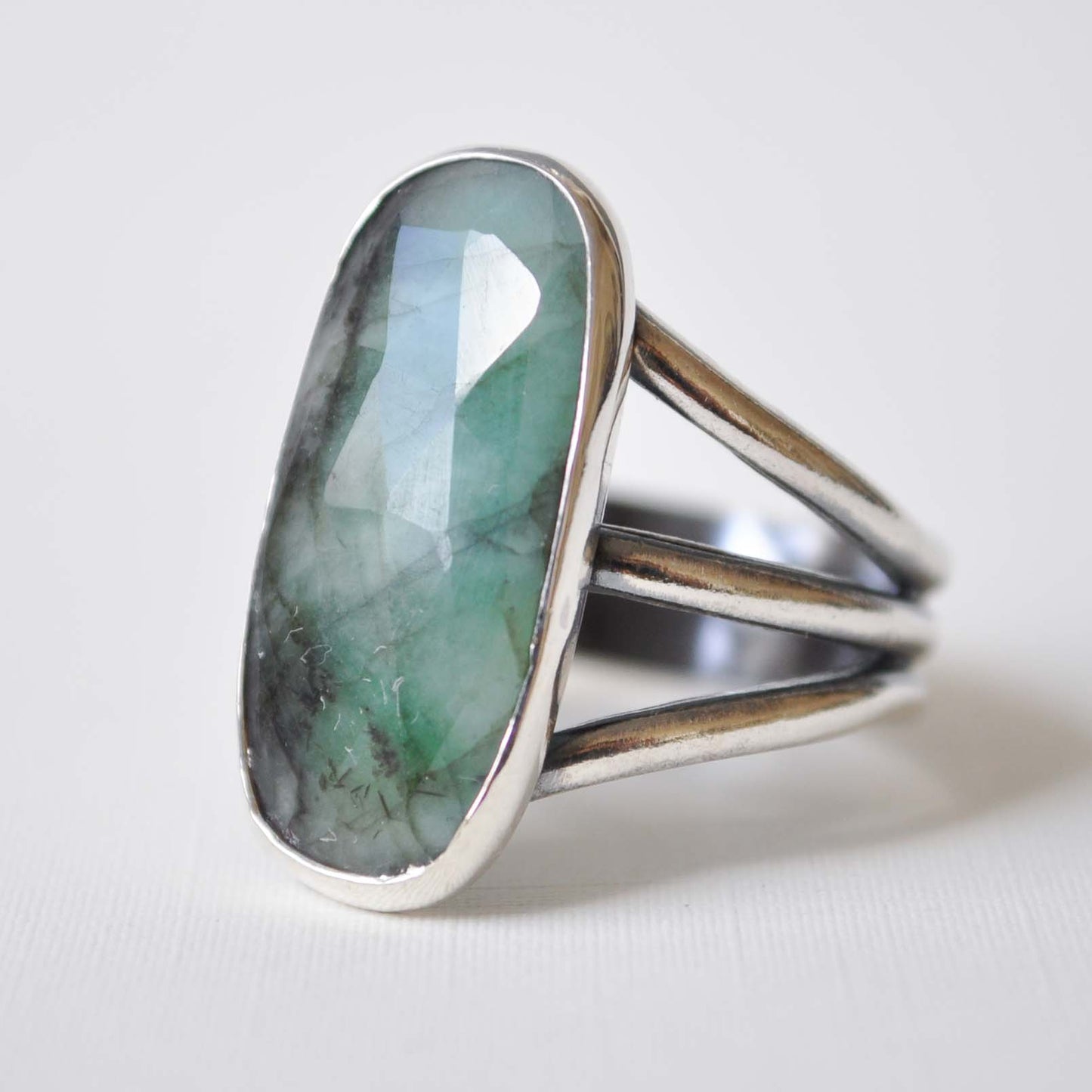 Silver ring with a green gemstone on a white background