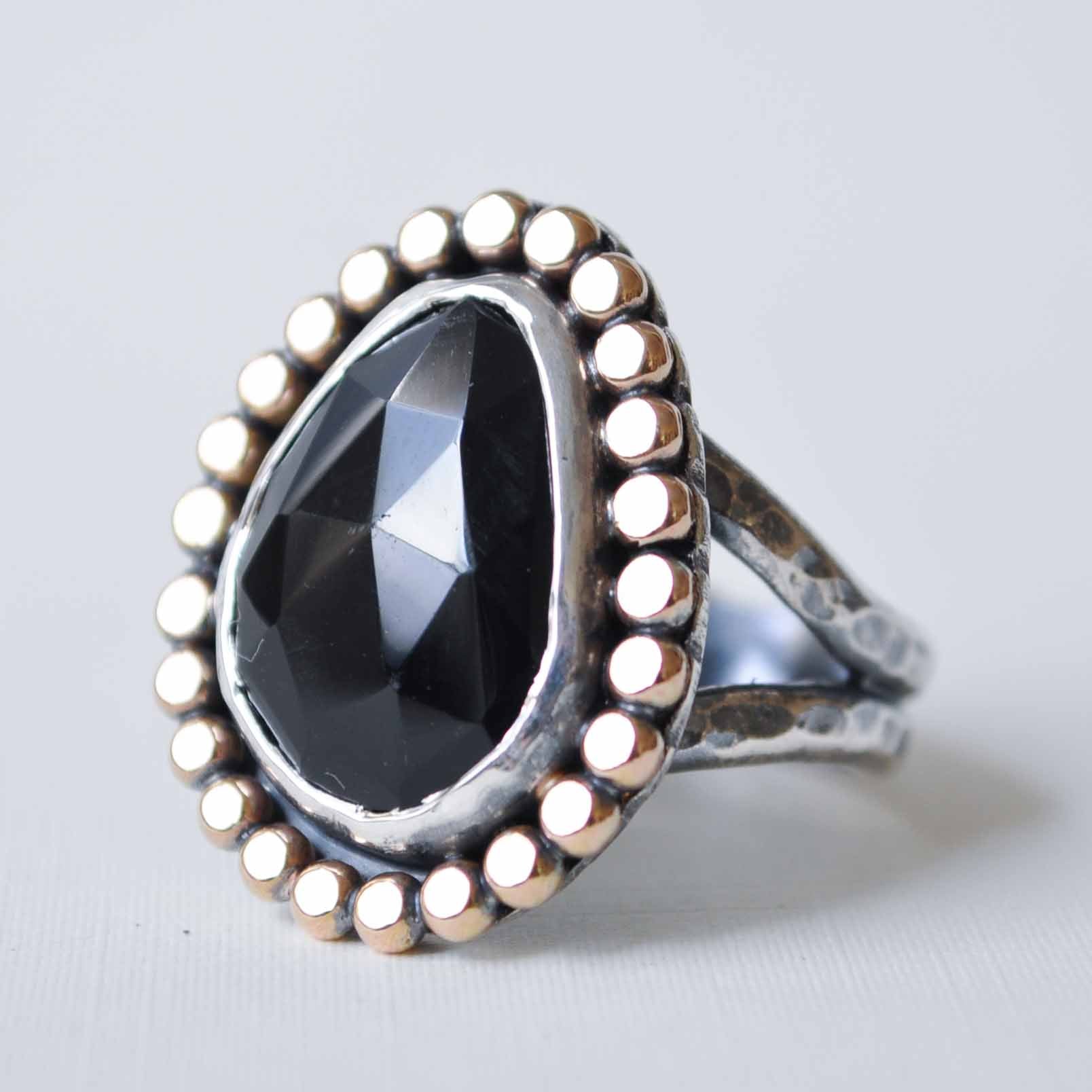 Silver ring with a large black gemstone on a light gray background