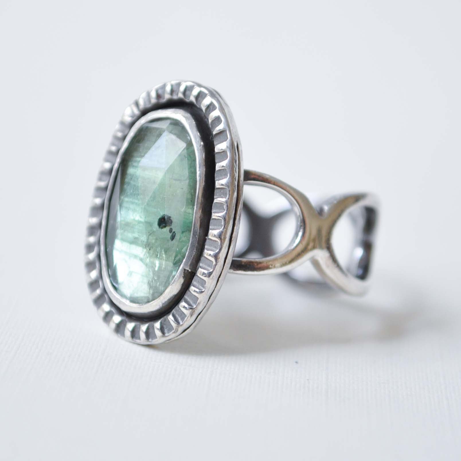 Silver ring with a green gemstone on a white background