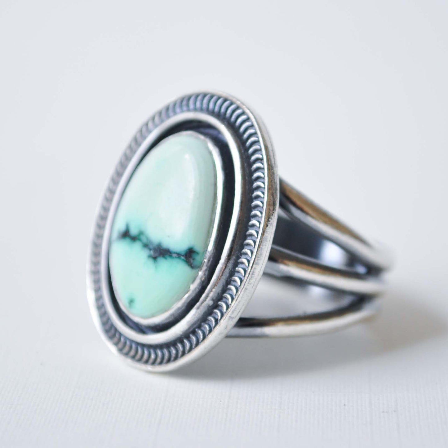Silver ring with a turquoise stone on a light gray background