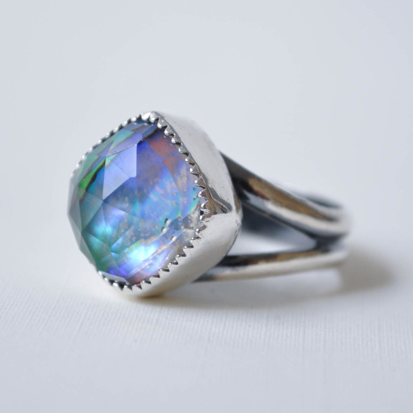 Silver ring with a colorful gemstone on a light gray background