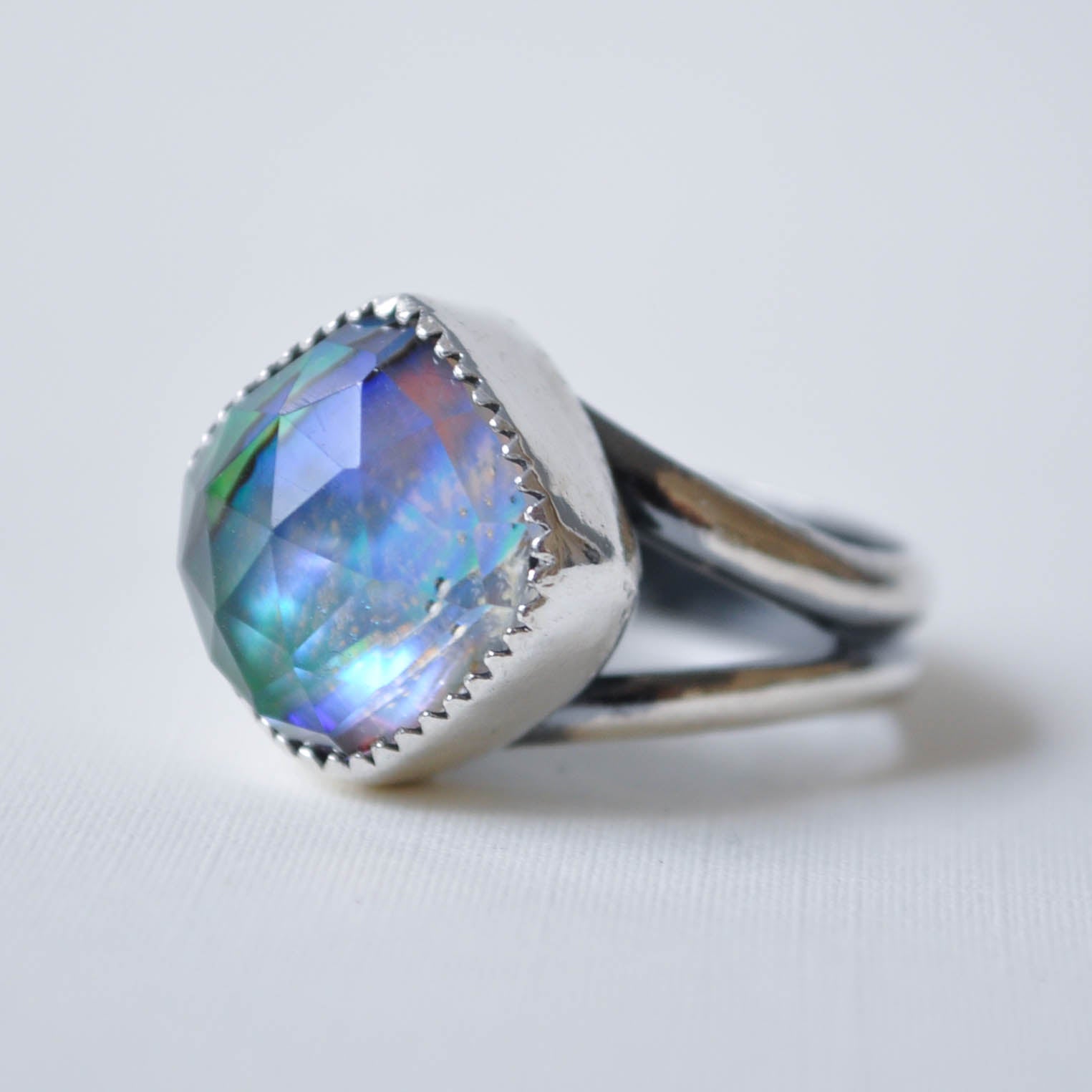 Silver ring with a colorful gemstone on a light gray background