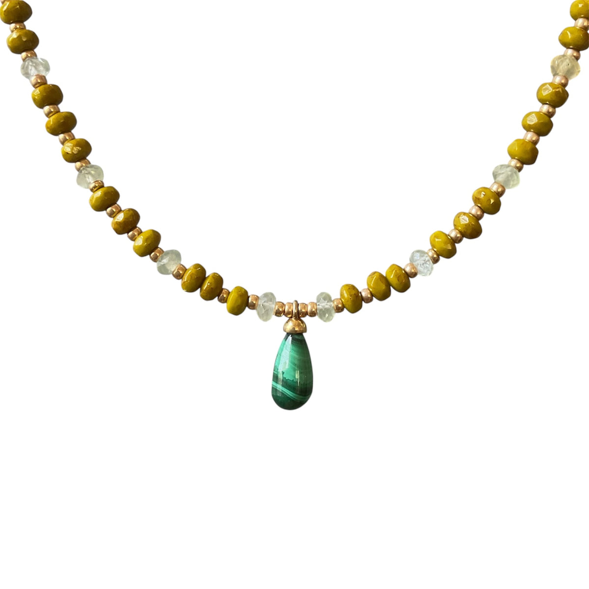 A beaded necklace featuring olive green and yellow faceted beads, clear crystal-like beads, and a central teardrop-shaped green stone pendant with gold-toned metal accents, shown against a plain white background.