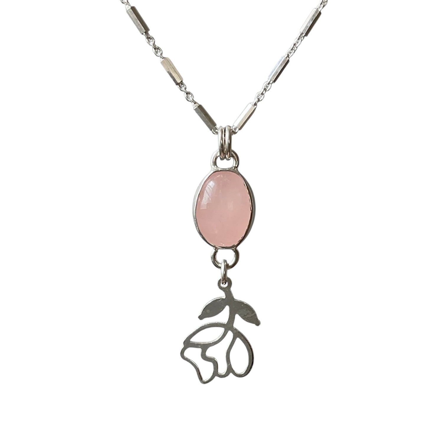 Necklace with a pink stone pendant and floral charm on a white background