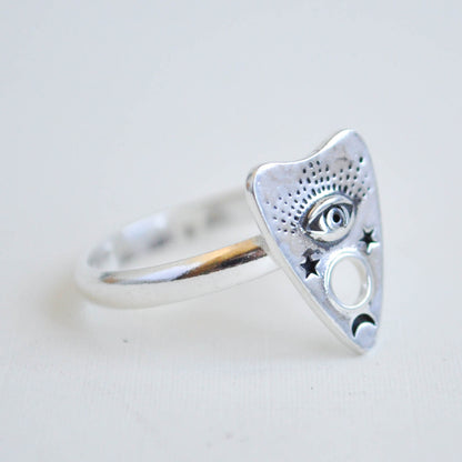 Silver triangle-shaped ring with eye design on a light gray background