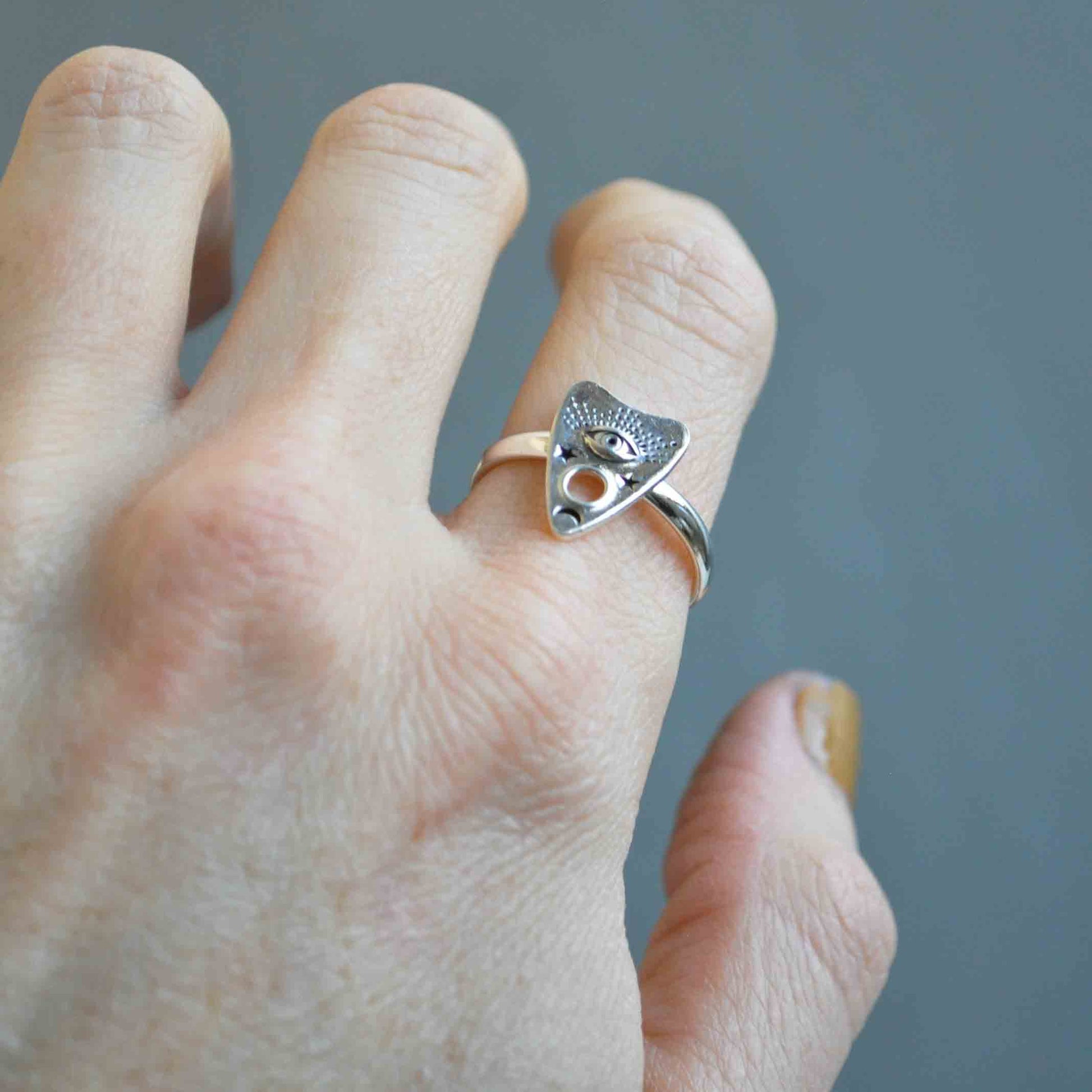 Silver ring with a unique design worn on a finger against a blurred background