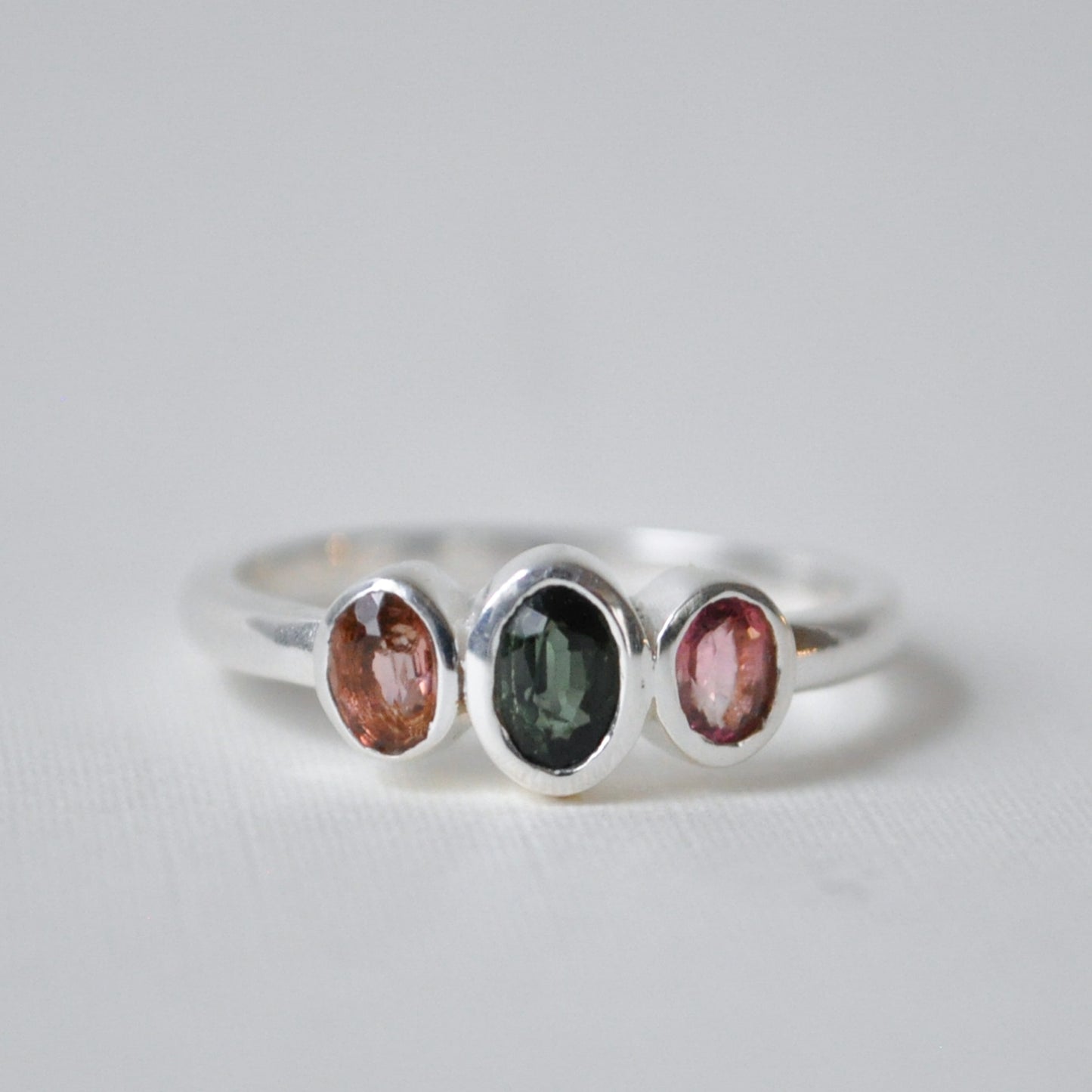 Silver ring with three round gemstones on a light gray background