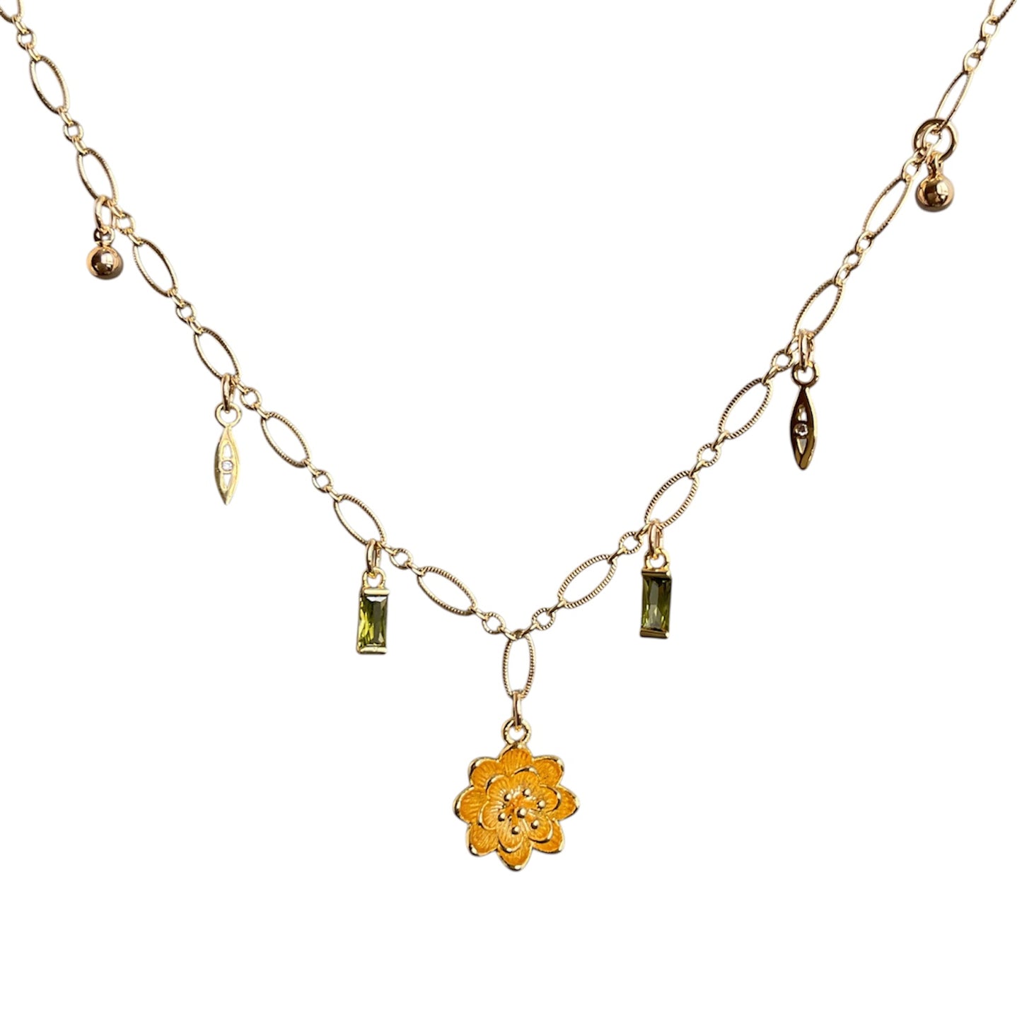 Gold necklace with a flower pendant and green gemstones on a white background