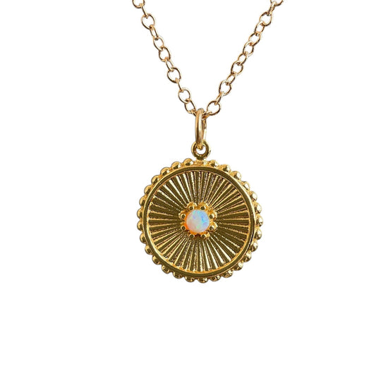 Gold necklace with a circular pendant featuring a central opal gemstone on a white background