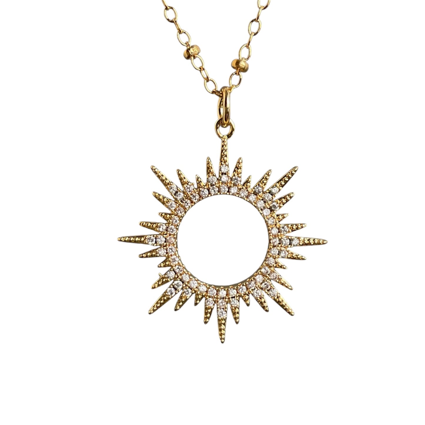 Gold sun-shaped pendant necklace on a white background