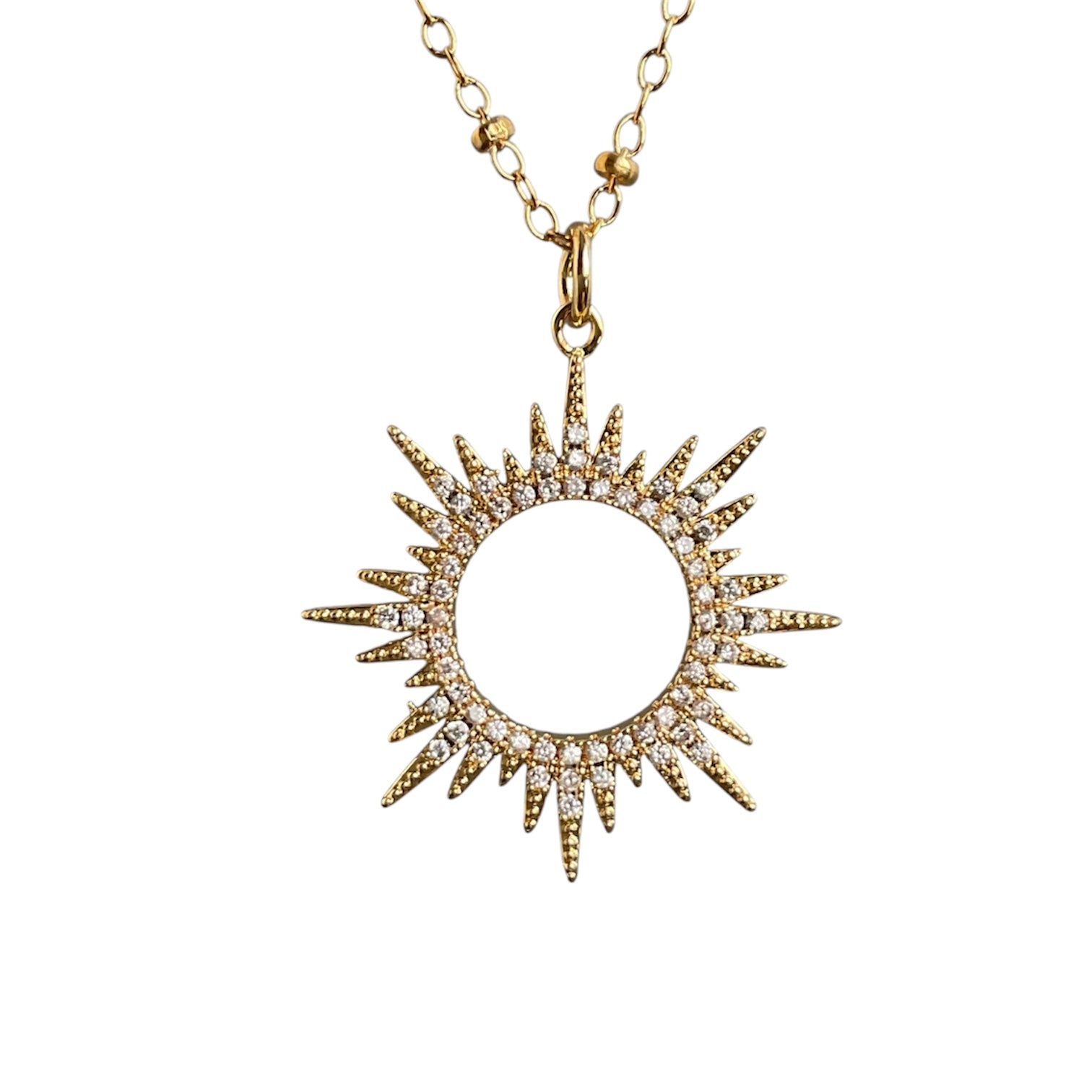 Gold sun-shaped pendant necklace on a white background