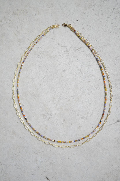 Necklace with multicolored beads and gold chain on a gray surface