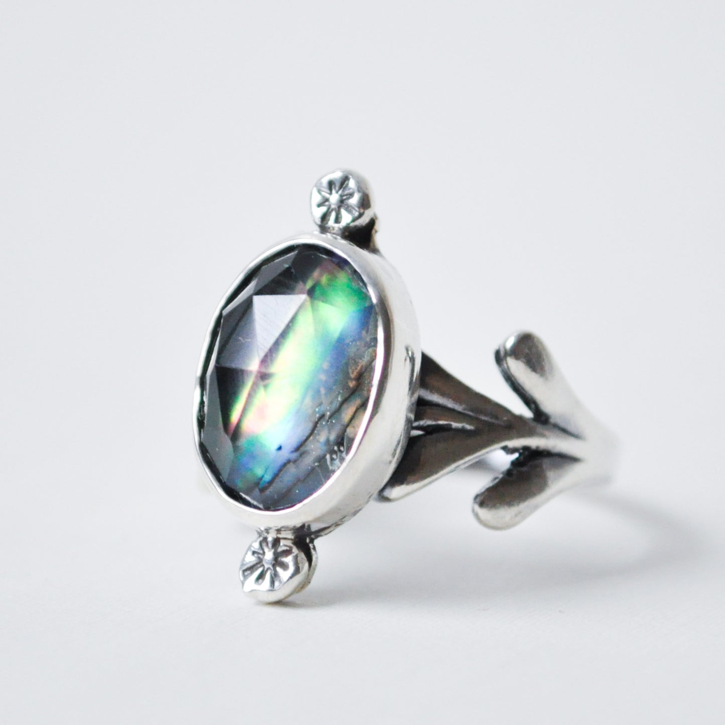 Silver ring with a large gemstone on a light gray background