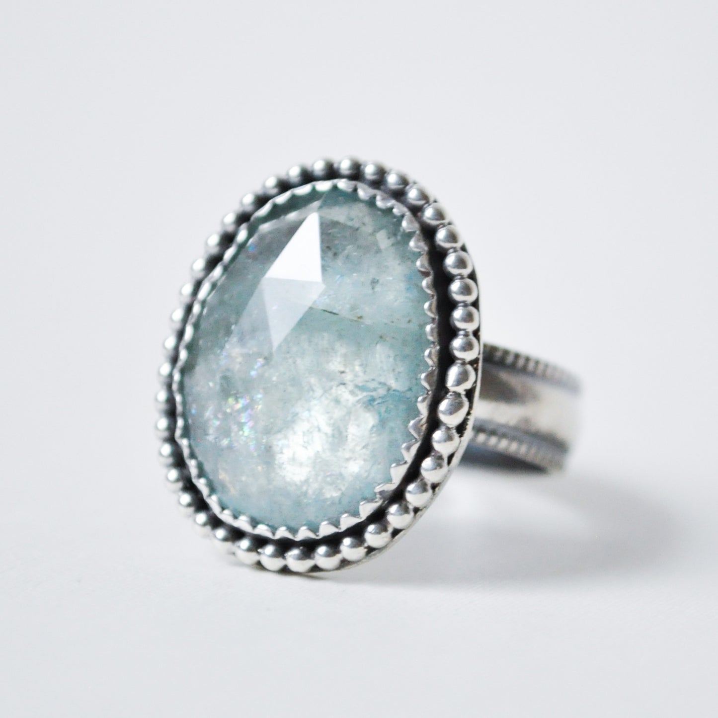 Ring with a light blue gemstone and silver band on a white background