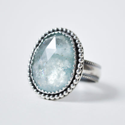 Ring with a light blue gemstone and silver band on a white background