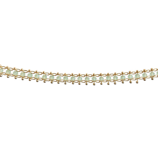 Gold bracelet with green beads on a white background