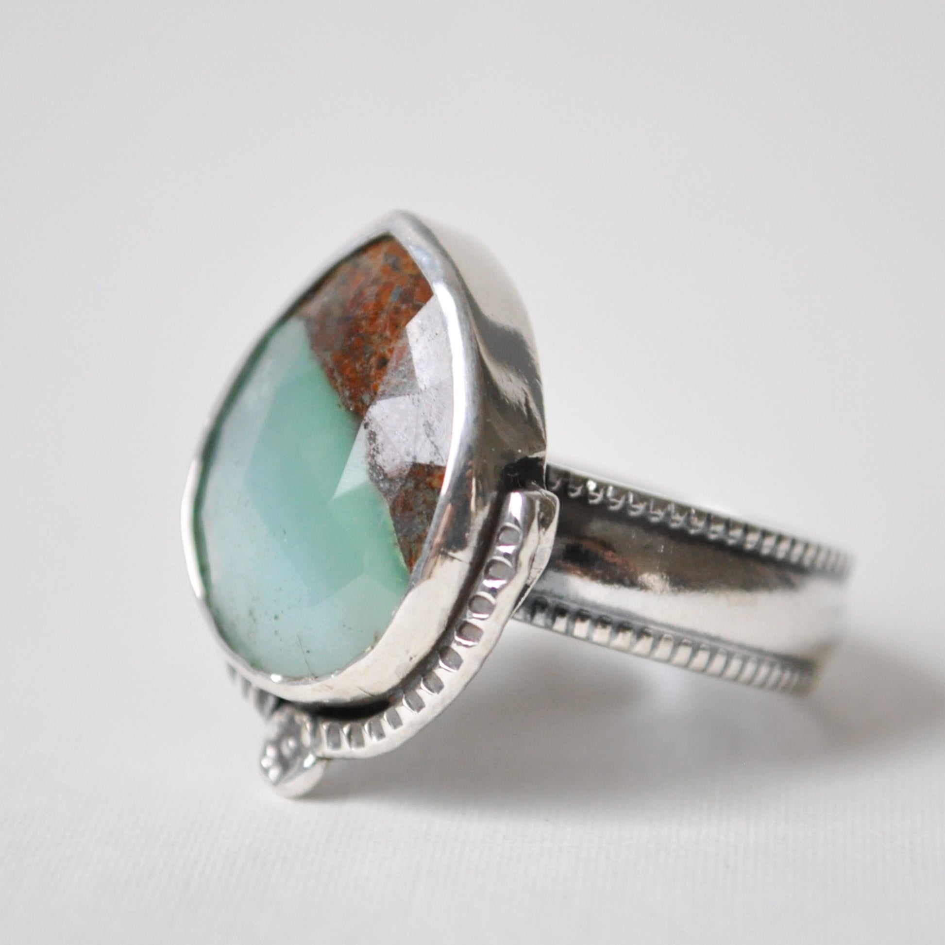 Silver ring with a large green stone on a white background
