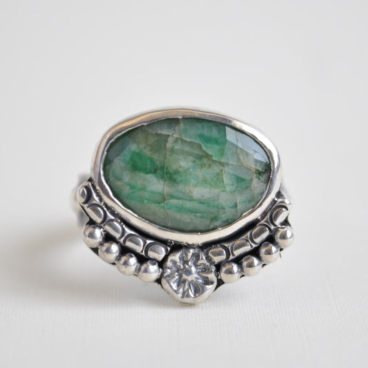 Silver ring with a green gemstone on a white background