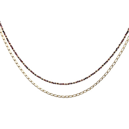 Layering necklace on a white background, one gold and one with small beads.