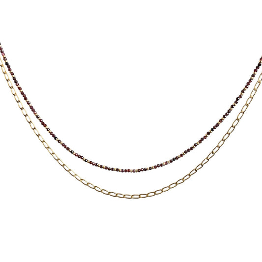 Layering necklace on a white background, one gold and one with small beads.