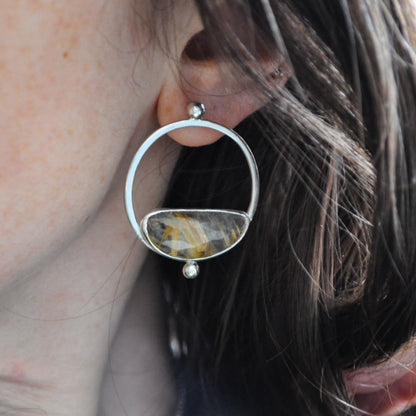Close-up of a silver earring with a gemstone worn by a person.