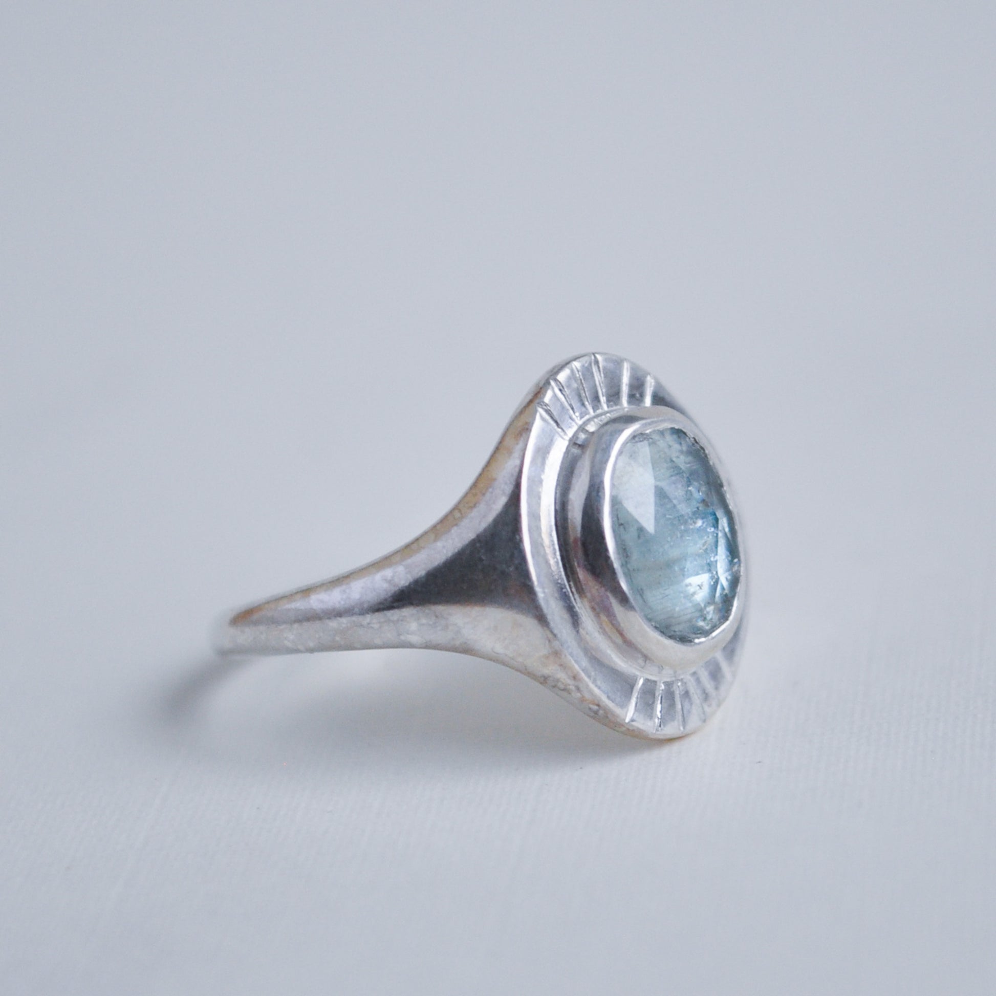 Silver ring with a blue gemstone on a light gray background