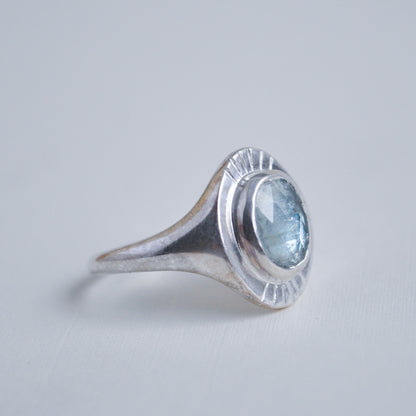 Silver ring with a blue gemstone on a light gray background