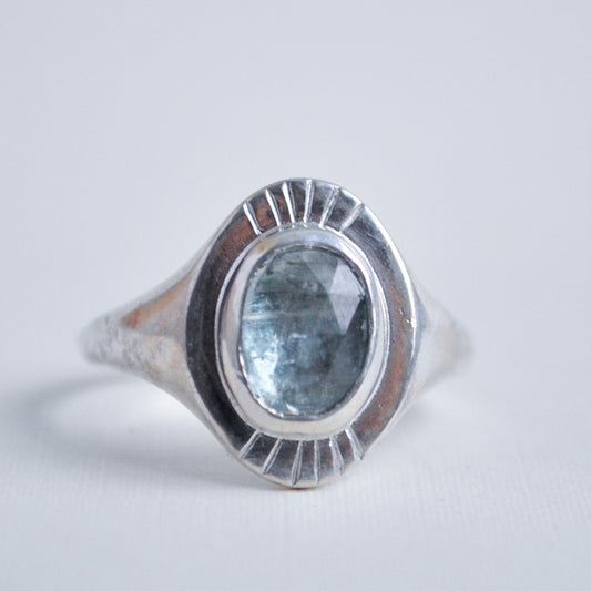 Silver ring with a blue gemstone on a light gray background
