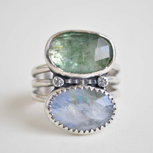 Silver ring with green and blue gemstones on a white background