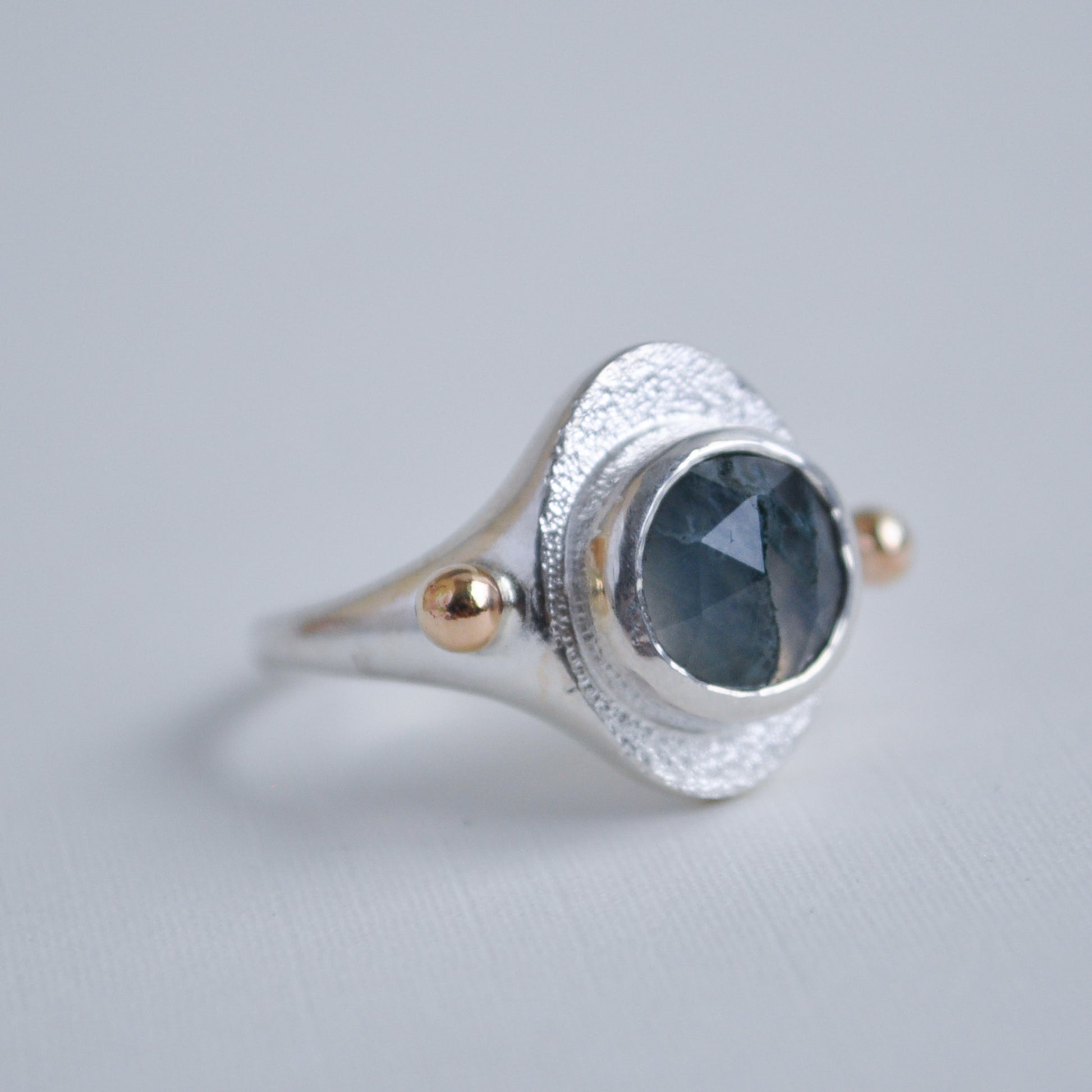 Silver ring with a green moss quartz gemstone on a gray background