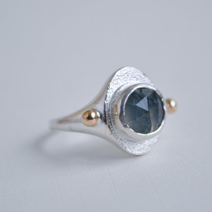 Silver ring with a green moss quartz gemstone on a gray background