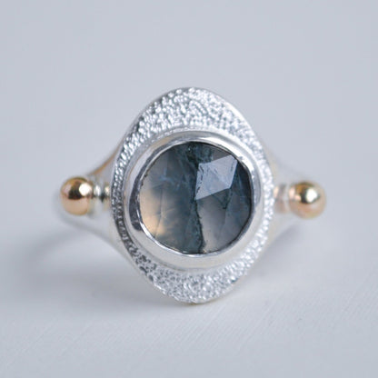 Silver ring with a green stone on a light gray background
