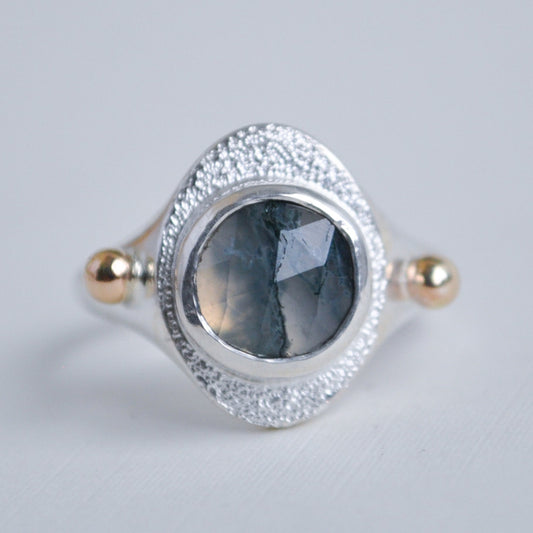 Silver ring with a green stone on a light gray background