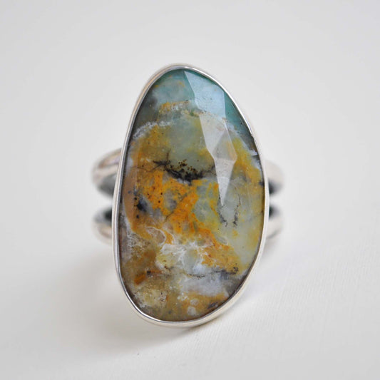 Ring with an oval stone featuring a natural blue, green and brown pattern on a white background