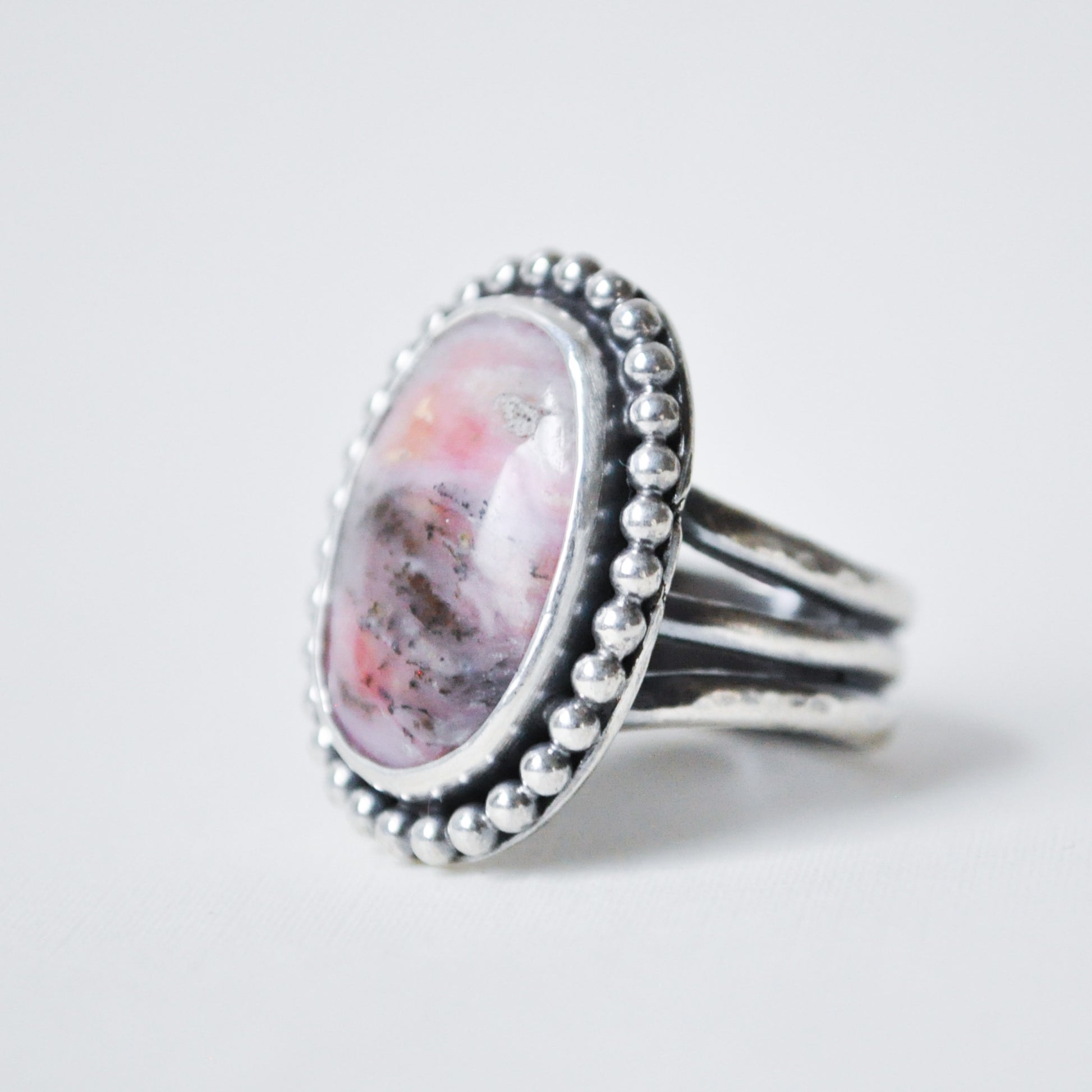 Silver ring with a pink stone on a white background