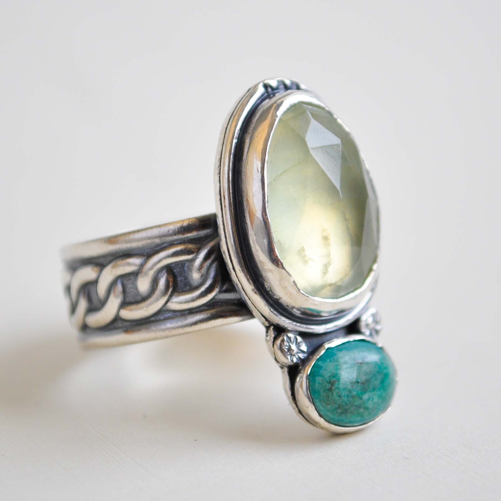 Silver ring with a green gemstone on a light background