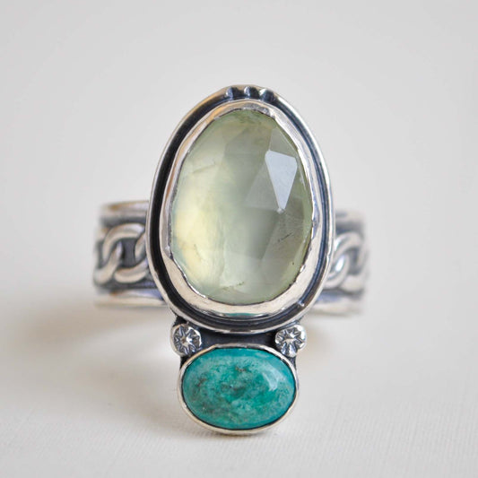 Silver ring with green and blue stone on a white background