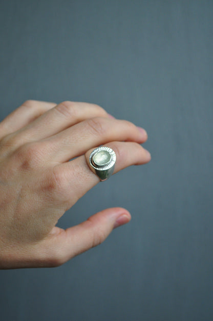 Hand wearing a silver ring with a dark gray background
