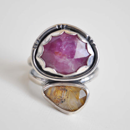Silver ring with pink and yellow gemstones on a white background