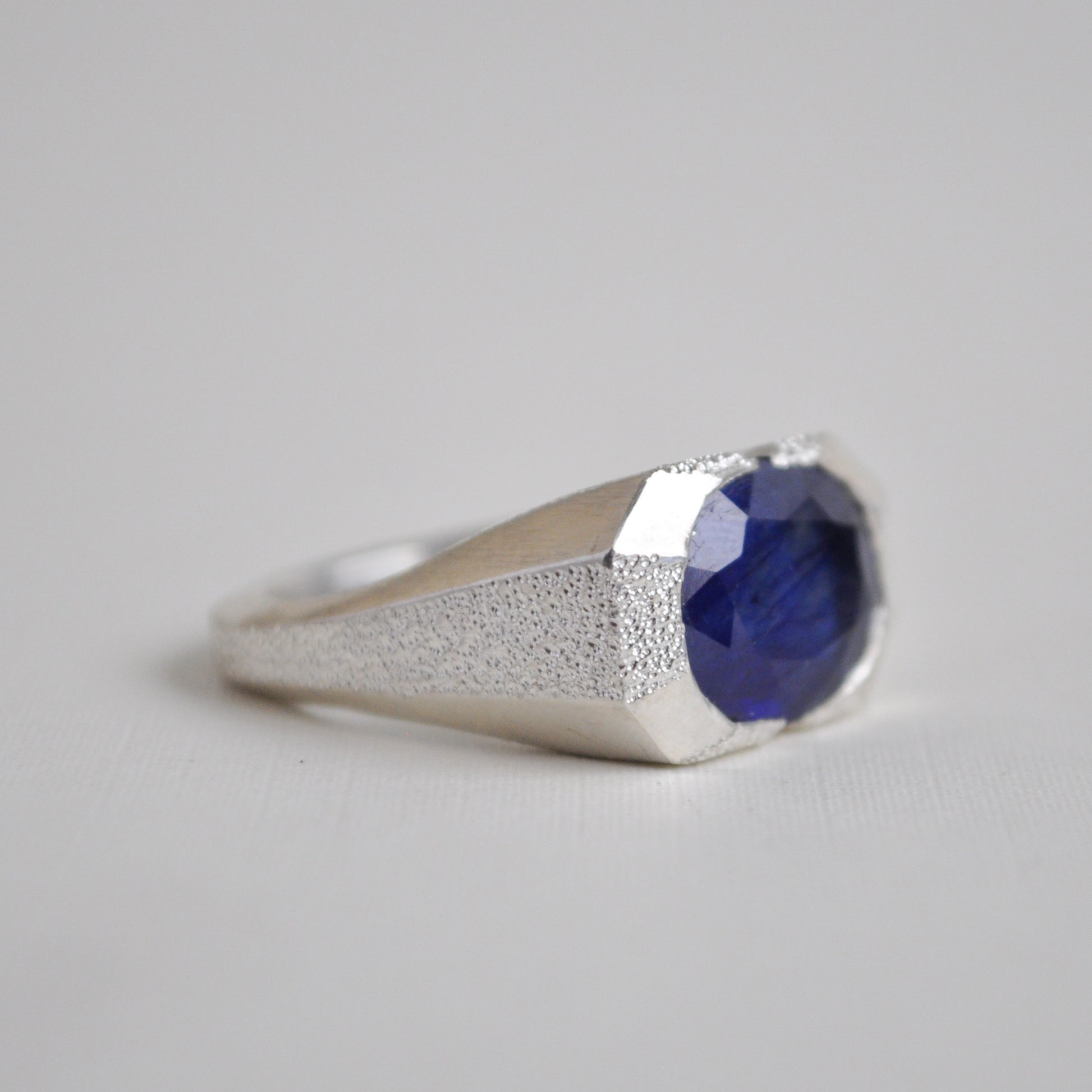 Silver ring with a blue gemstone on a light gray background