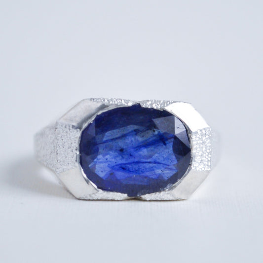 Ring with a blue gemstone and silver band on a light gray background