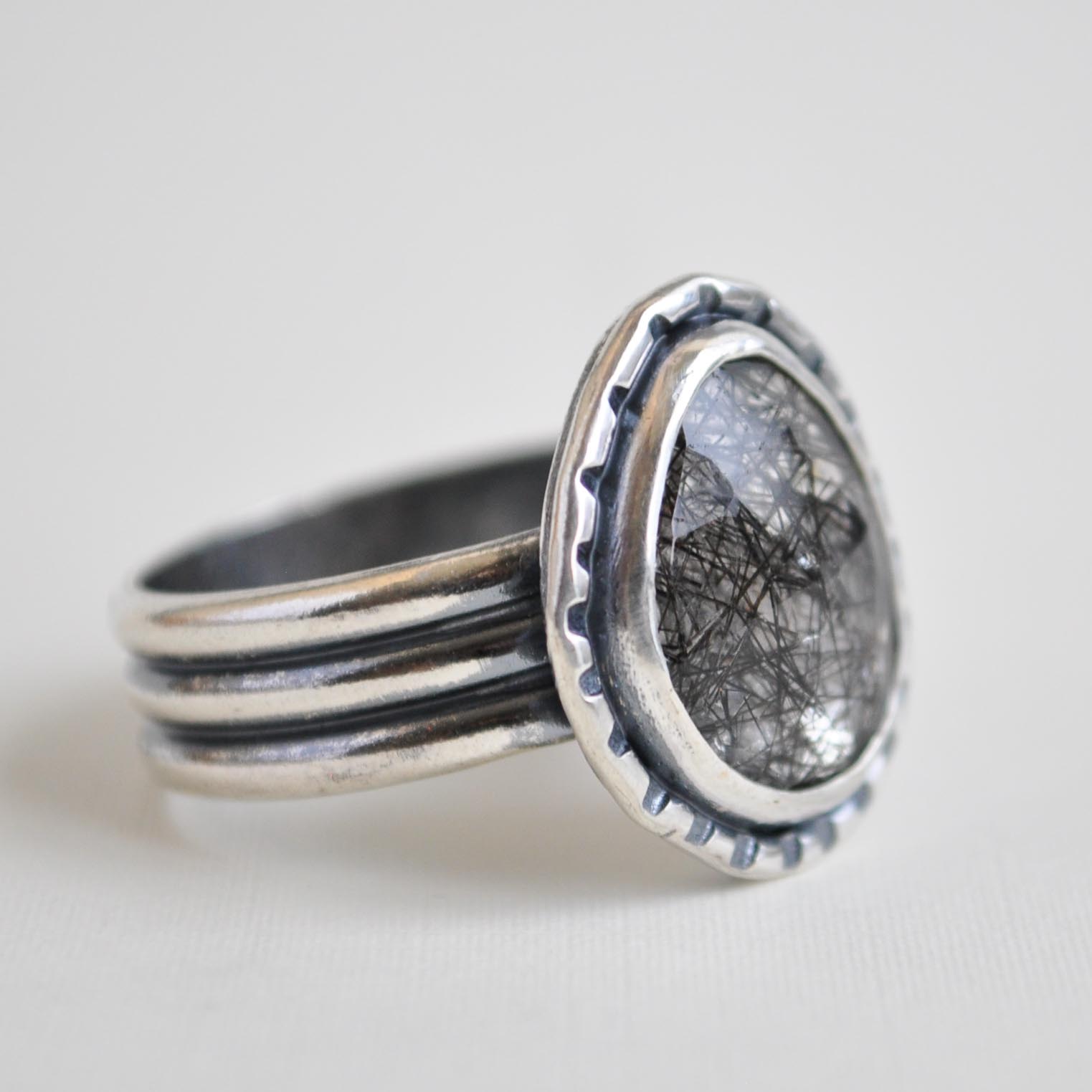 Silver ring with textured band on a light gray background