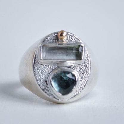 Silver ring with blue gemstone and gold accent on a light gray background