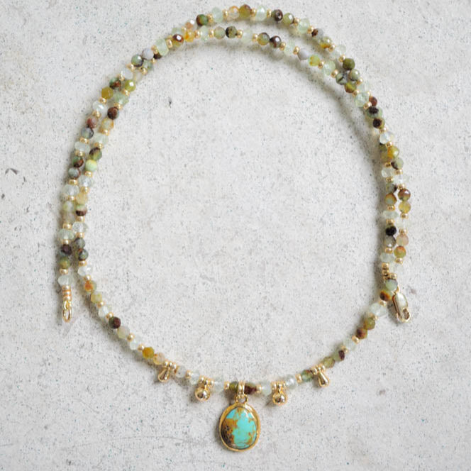 Necklace with turquoise and chrysoprase gemstones and a centered pendant on a light gray background