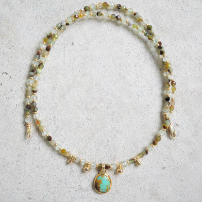 Necklace with turquoise and chrysoprase gemstones and a centered pendant on a light gray background