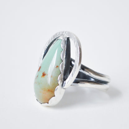 Silver ring with a green stone on a white background