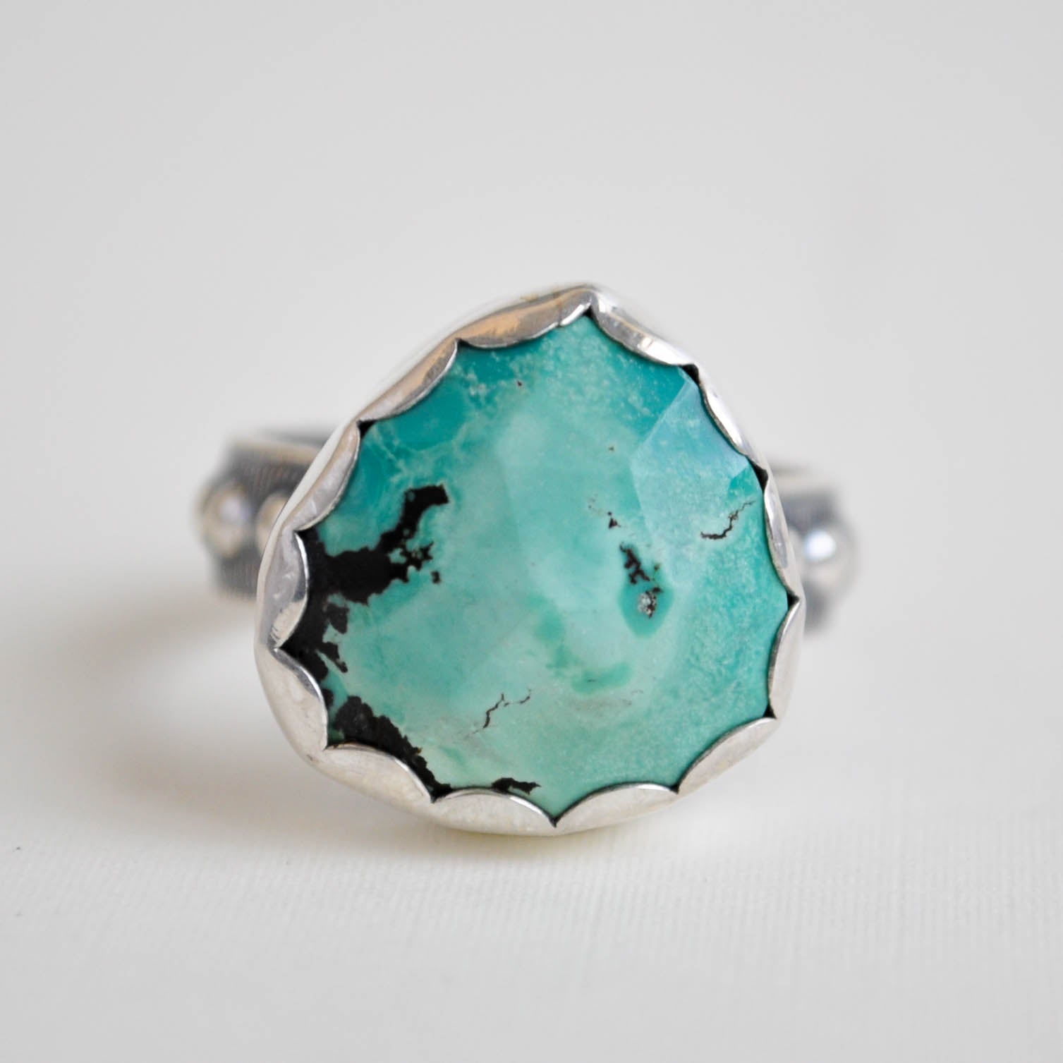 Turquoise ring with silver band on a light gray background